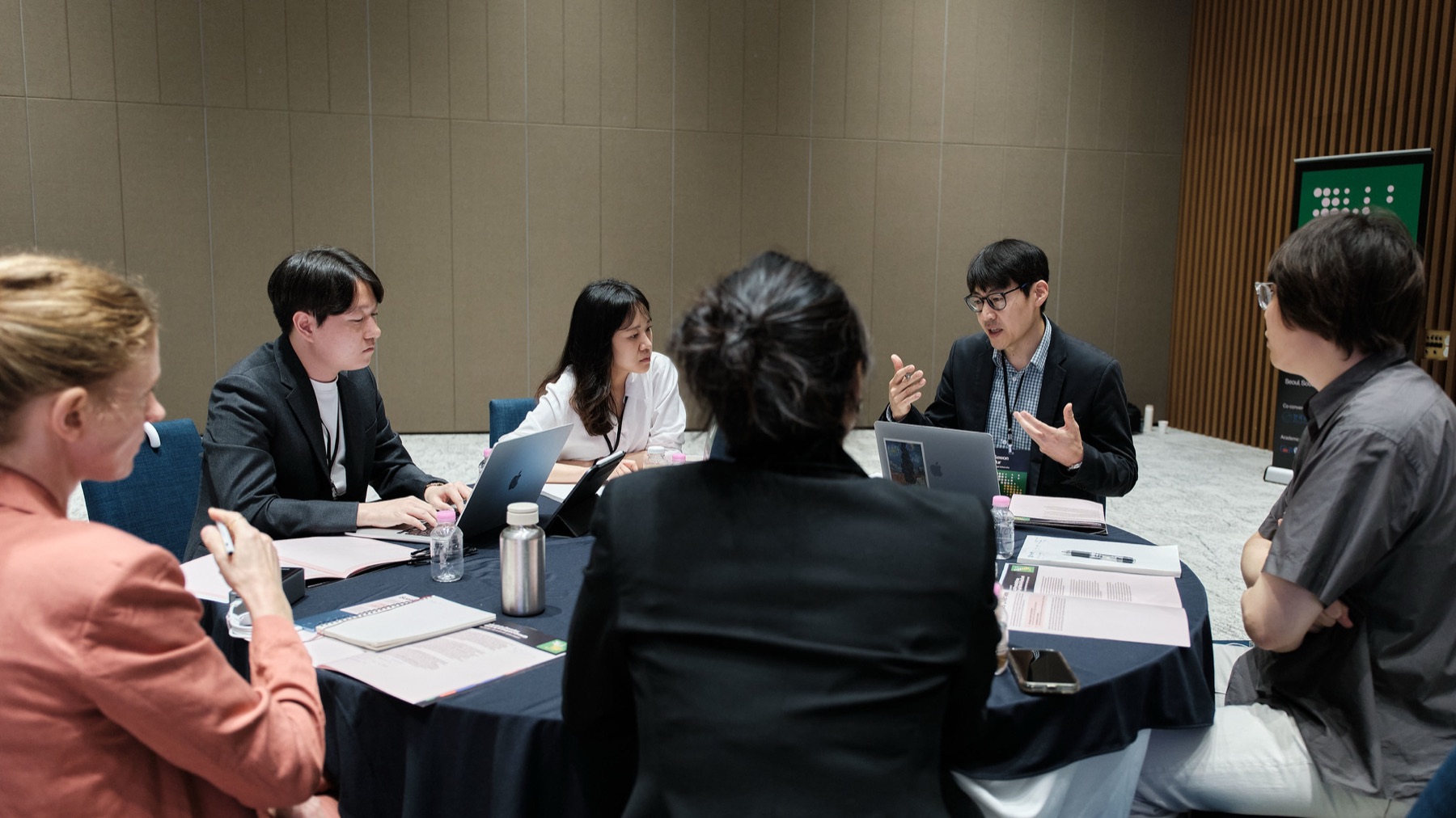 Sewon Hur speaking to participants seated around a table during an AI scenario workshop in Seoul